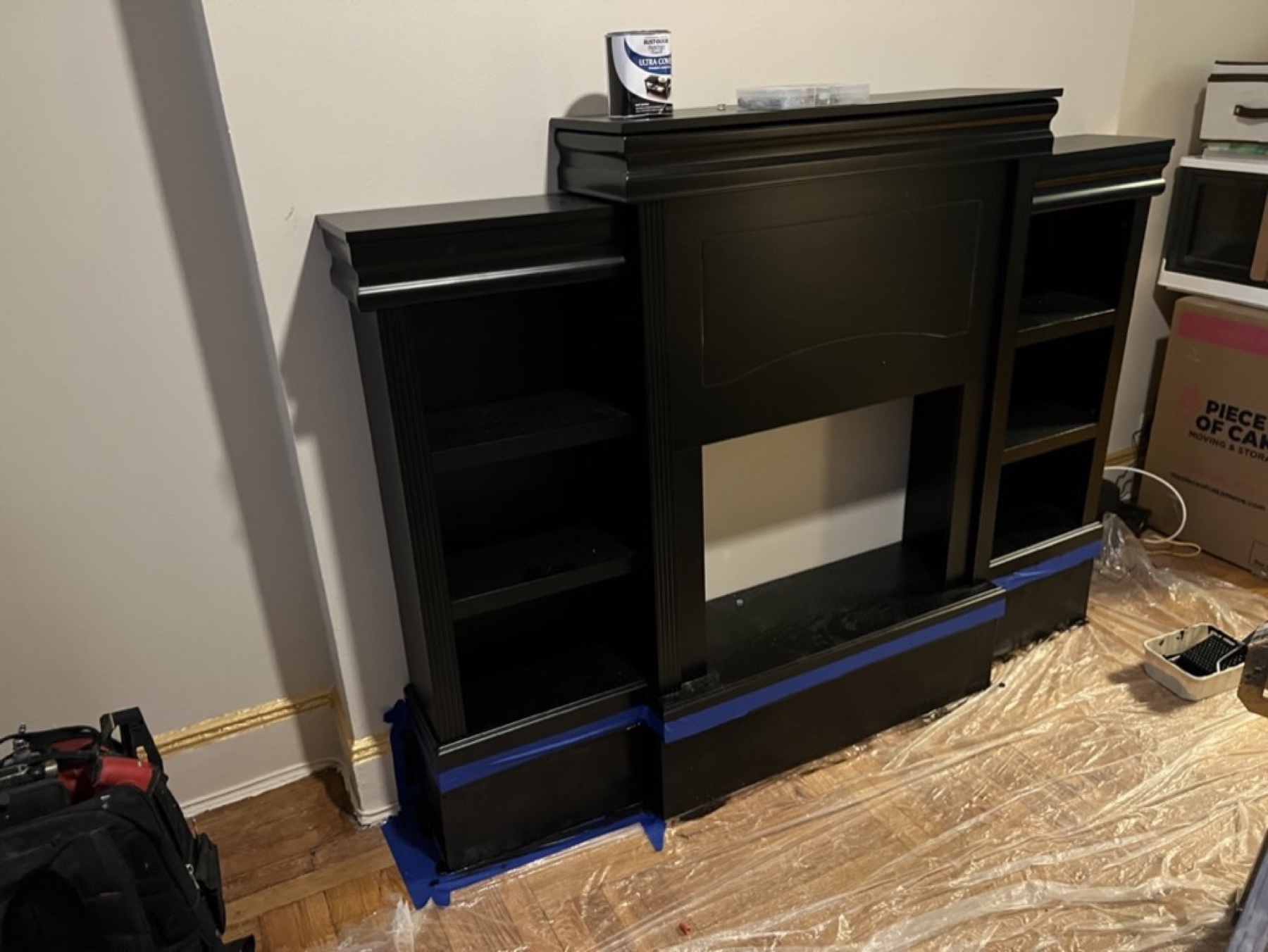 Fireplace cabinet during work with floor protection and blue tape in place
