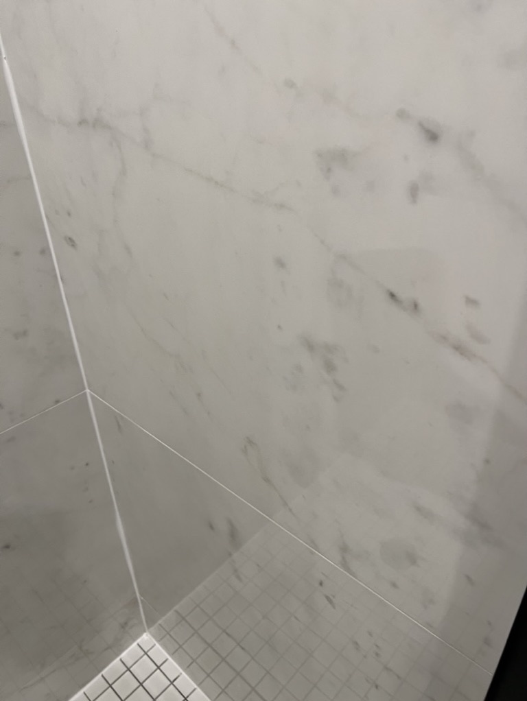 Related views of marble-look shower tile and a recessed shelf