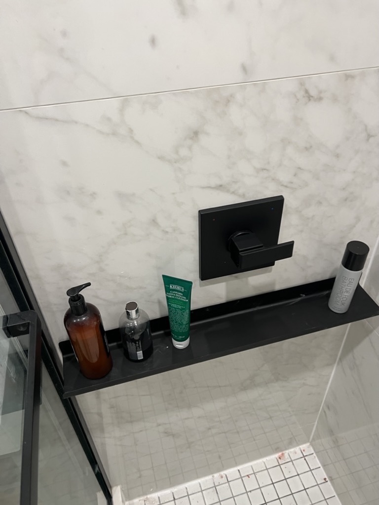 Related views of marble-look shower tile and a recessed shelf