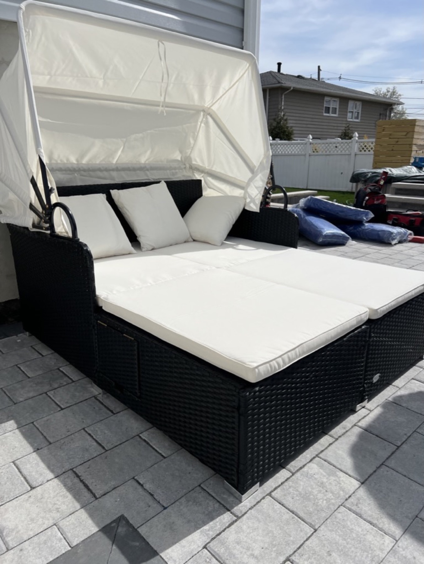 Completed black canopy daybed with white cushions on a patio